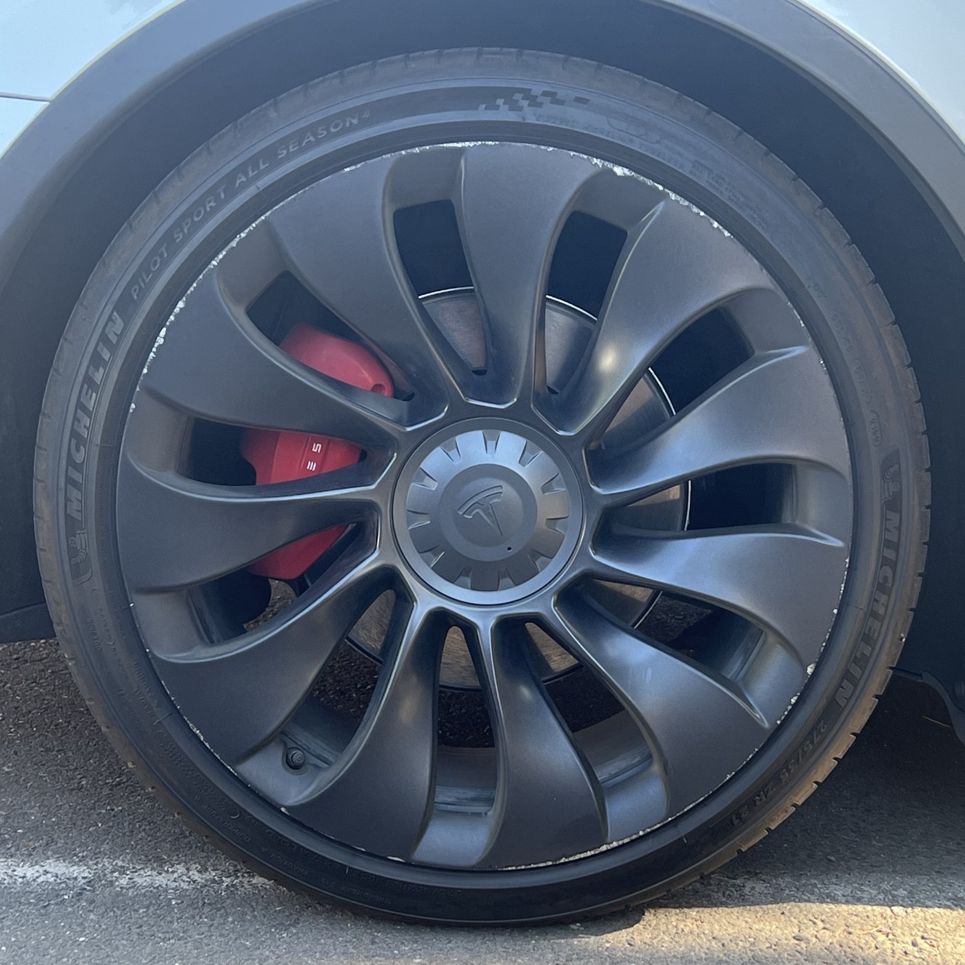 Tyre and wheel with a visible red brake assembly on a Tesla