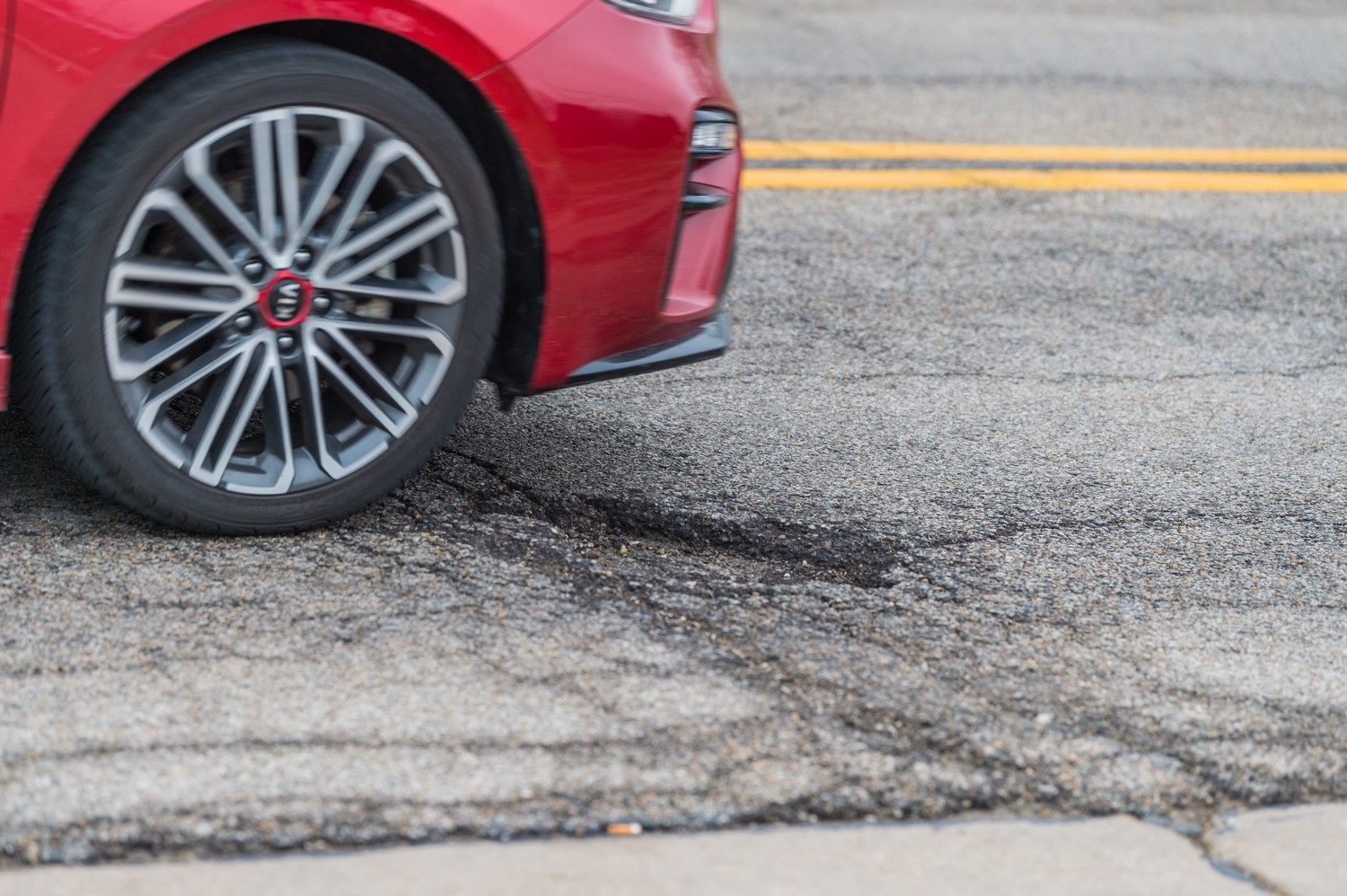 Car wheel beside a damaged road surface
