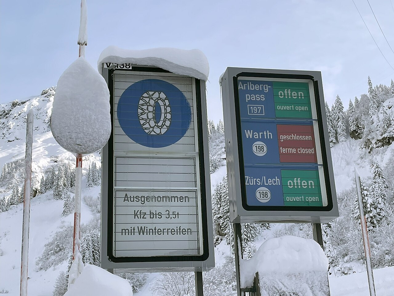 Winter-equipment signs beside a snowy Alpine road